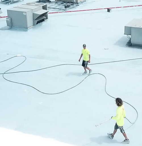 Roofers apply roof restoration coating.